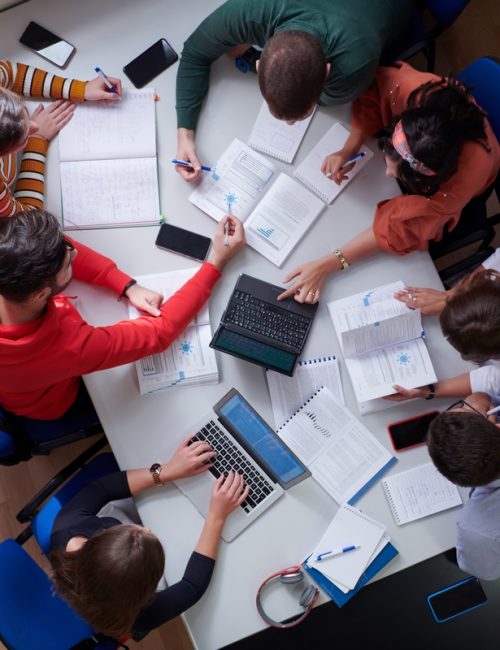 Top view of university students sitting at a table studying and working on laptop